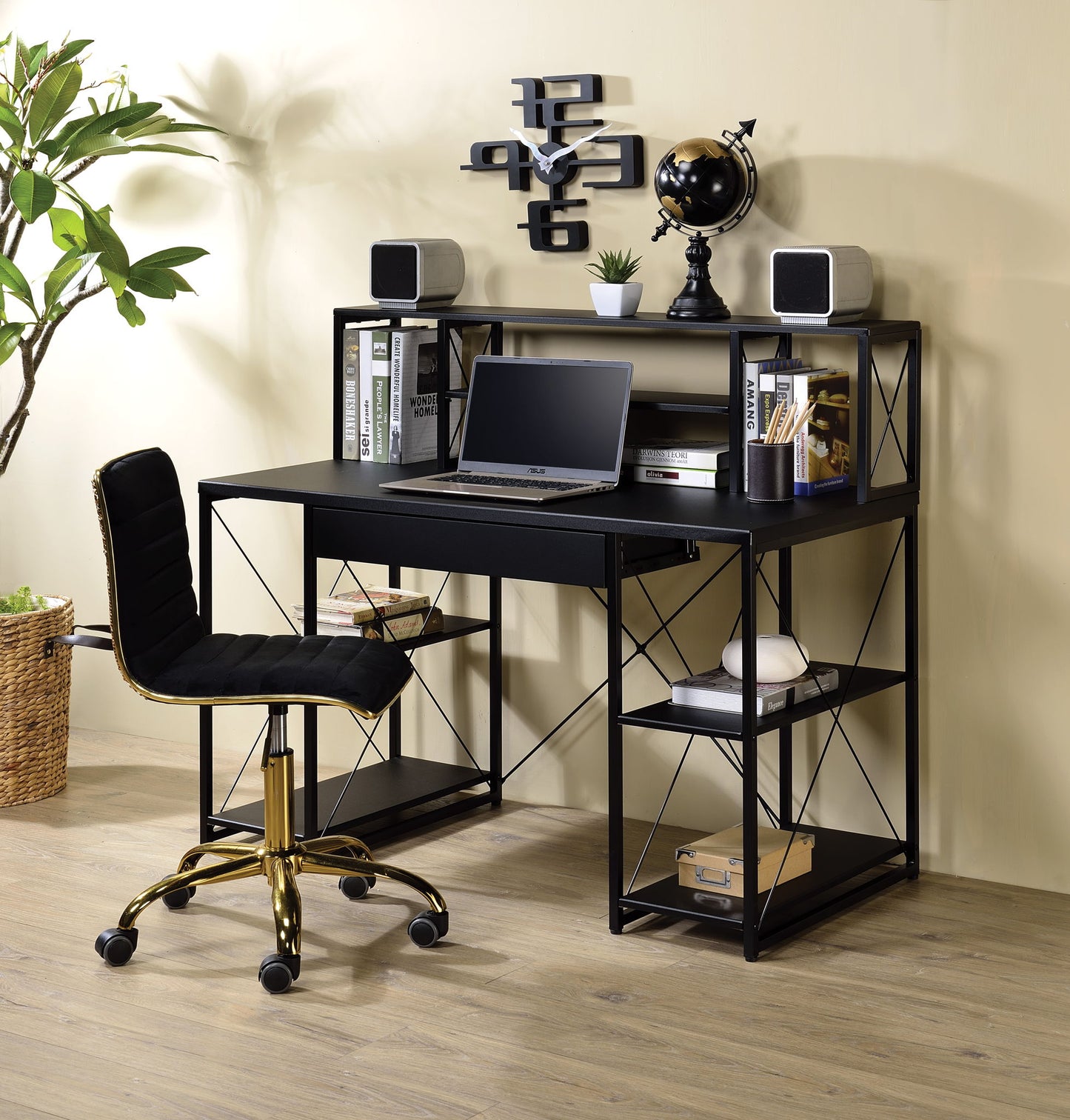 The Amiel All Purpose Writing Desk, featuring open shelves for books and décor, is paired with a stylish black chair with gold legs. A geometric wall clock and a potted plant accent the modern setup on warm wooden flooring.