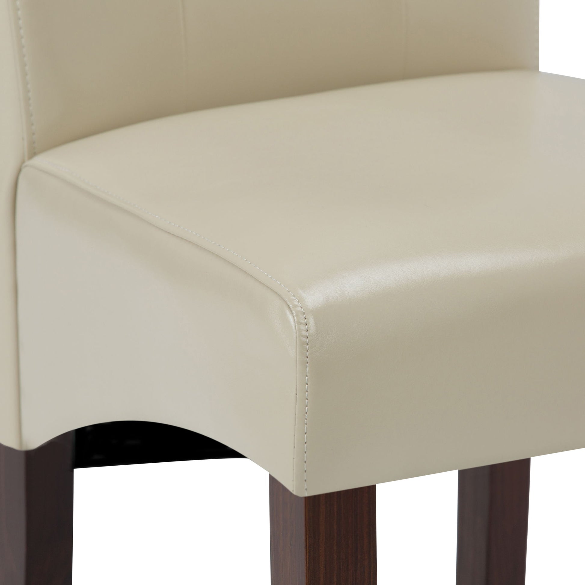 Close-up of the Cosmopolitan Deluxe Tufted Parson Upholstered Chair seat, featuring cream-colored fabric, wooden legs, smooth stitching, and curved edges.
