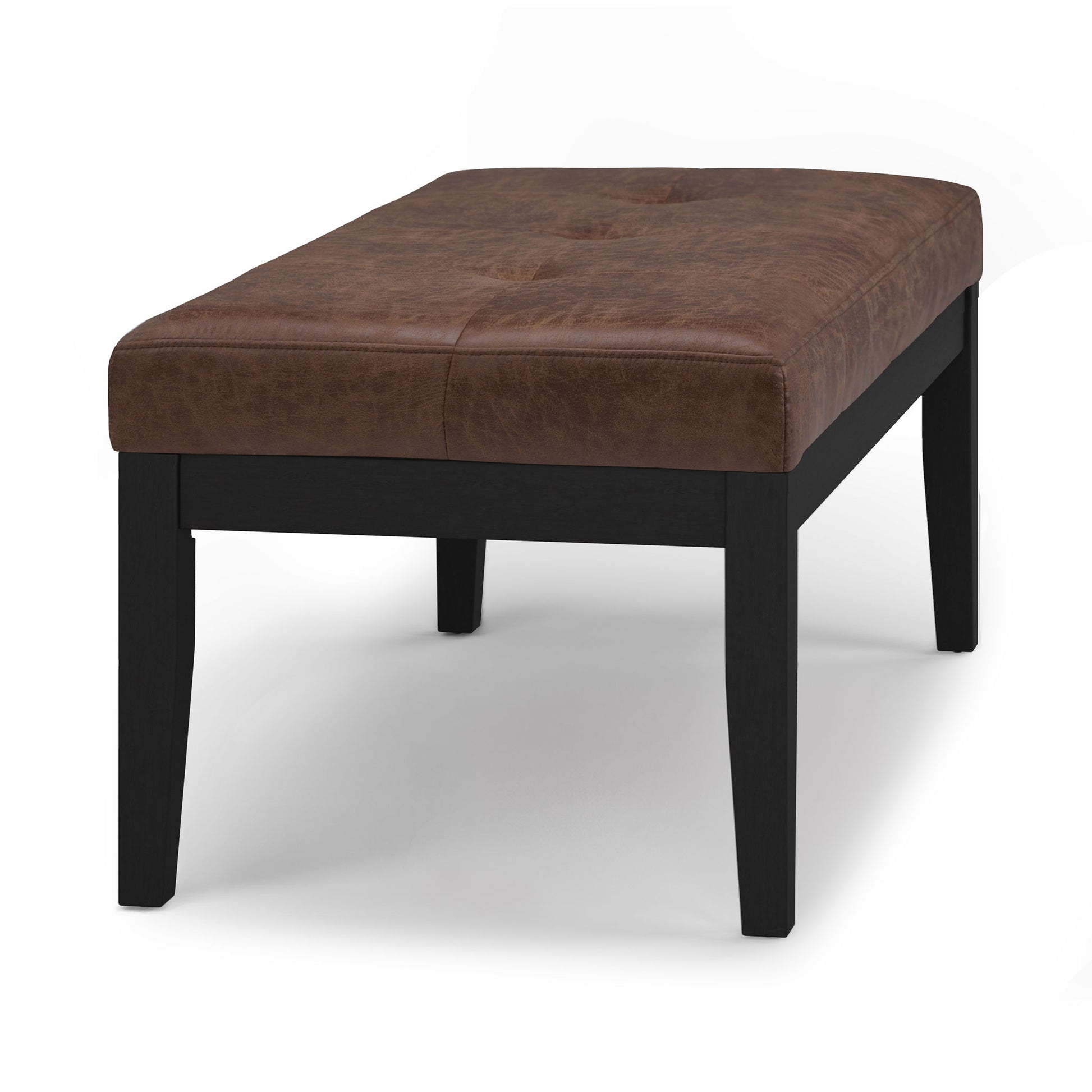 The Lacey - Upholstered Tufted Ottoman Bench features a rectangular cushioned brown leather seat with four black wooden legs, displayed against a plain white background.
