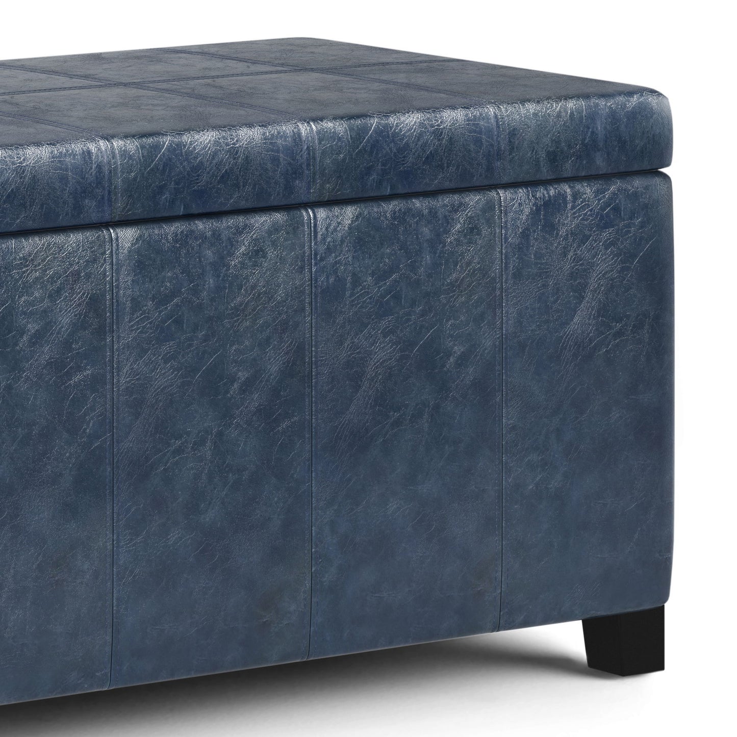 Close-up of the Dover - Upholstered Storage Ottoman Bench featuring dark blue faux leather, subtle surface stitching, and black wooden legs.