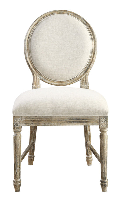 The Ludin Upholstered Dining Chairs (Set of 2) feature round, cushioned backs and seats in light beige fabric, with brown wooden frames showcasing a distressed finish and carved floral details.