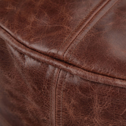 Close-up of the Connor Handcrafted Round Pouf’s brown, textured leather upholstery featuring visible stitching and natural creases.