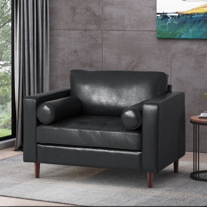 The Sophisticated Club Chair With Relaxing Comfort, featuring black leather and cylindrical cushions on wooden legs, sits by a round side table in a gray-walled room with curtains and an abstract painting.