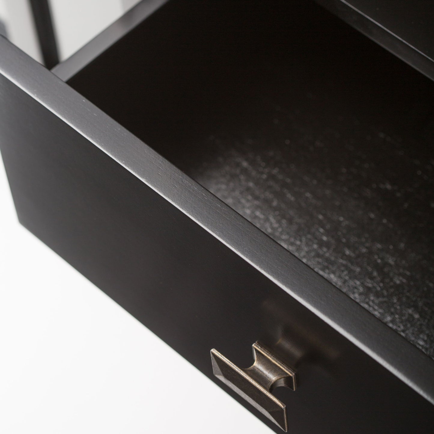 A close-up view of an open, empty black drawer with a metallic handle from the Artisan Handcrafted Tall TV Media Stand, shown against a plain white background.