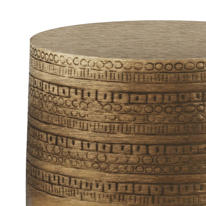 A close-up of the Johnsen - Handcrafted Large Metal Accent Table, featuring a cylindrical metallic gold body with raised geometric bands of circles and lines wrapping horizontally around its surface.