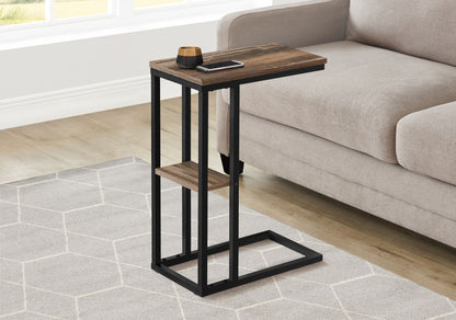 The Accent Table C-Shaped, Contemporary & Modern with a dark wood top and black metal frame sits next to a beige sofa on a light geometric-patterned rug, holding a phone and small cup.