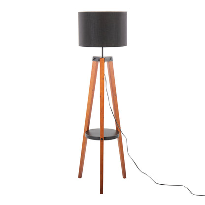 The Compass Mid Century Modern Floor Lamp features a black drum shade, wooden tripod legs, a round black shelf at the center, and a black power cord extending from its base.