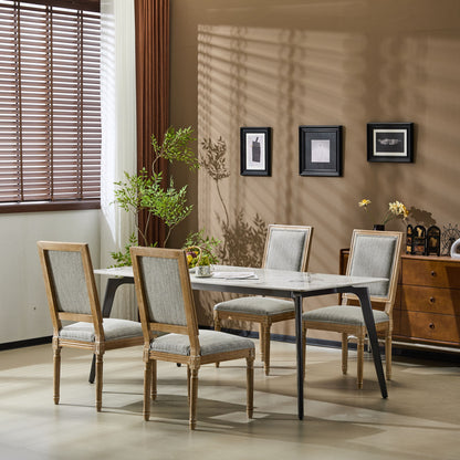A modern dining room featuring a rectangular marble table, five French Country Style Dining Chairs with upholstered seating and fluted legs, a potted plant, wall art, a sideboard, and sunlight casting shadows through wooden blinds.