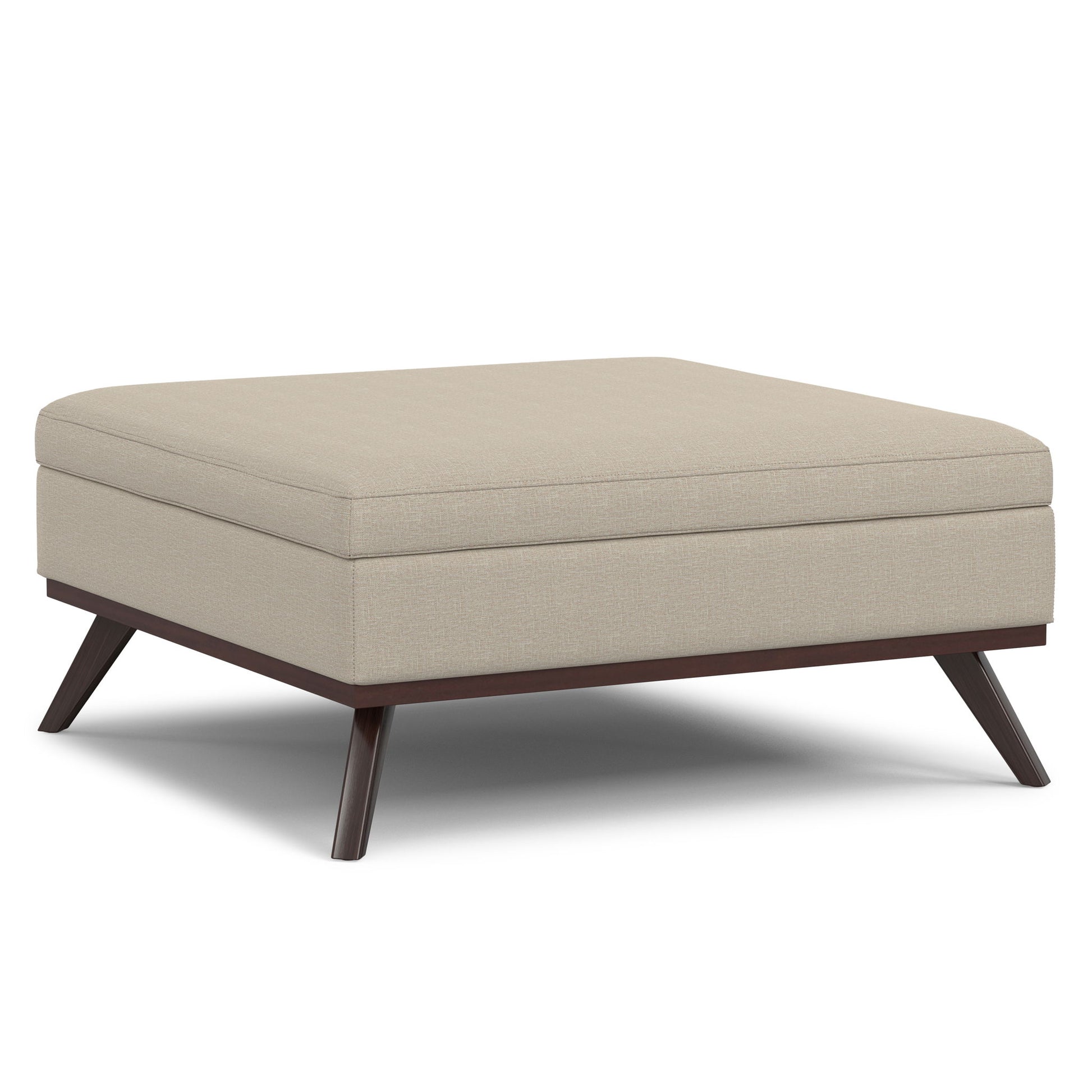 The Owen Multifunctional Square Coffee Table Storage Ottoman features light beige upholstery, a thick cushioned top, and dark wooden angled legs for a modern touch.