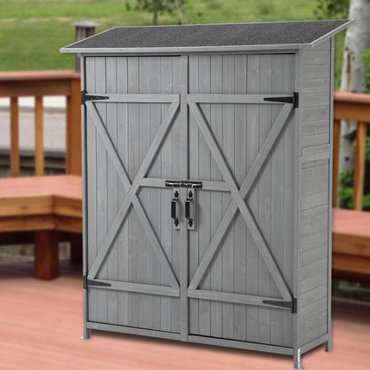 The Outdoor Storage Shed With Lockable Door, featuring detachable shelves and a pitch roof, stands on a wooden deck with railing, and green grass visible in the background.