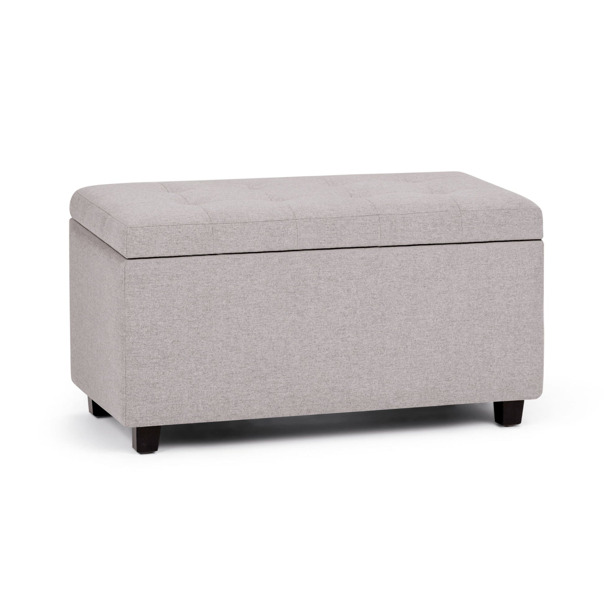 The Cosmopolitan Upholstered Storage Ottoman features a rectangular light gray design, cushioned tufted lid, and short dark wooden legs, shown against a white background.