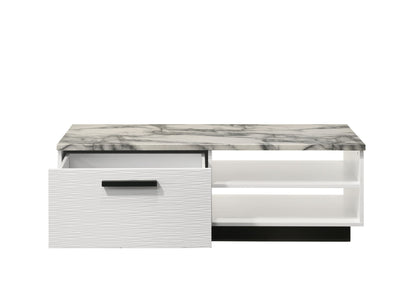 The Matilda Coffee Table features a modern white frame, a white faux marble top, one open drawer with a black handle on the left, and two open shelves on the right, all set against a white background.