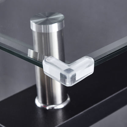 A Clear Glass Top Side Table with a modern design features a transparent corner protector on its edge and a metal support post behind the glass, set against a blurred, dark background.