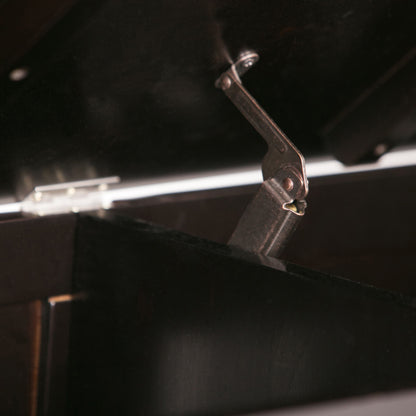 Close-up of a metal hinge mechanism attached to the black lid of the Brooklyn - Handcrafted Entryway Storage Bench, with part of the lid raised and the hinge arm visible.