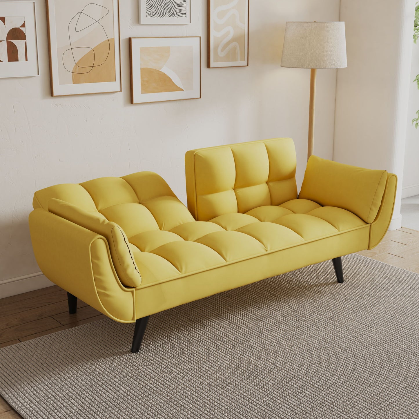 The Sofa Soft with two armrests and throw pillow offers comfort and a modern touch, fitting small spaces or apartments. It sits on a light gray rug with abstract art prints behind it, set against cream walls and wooden flooring.