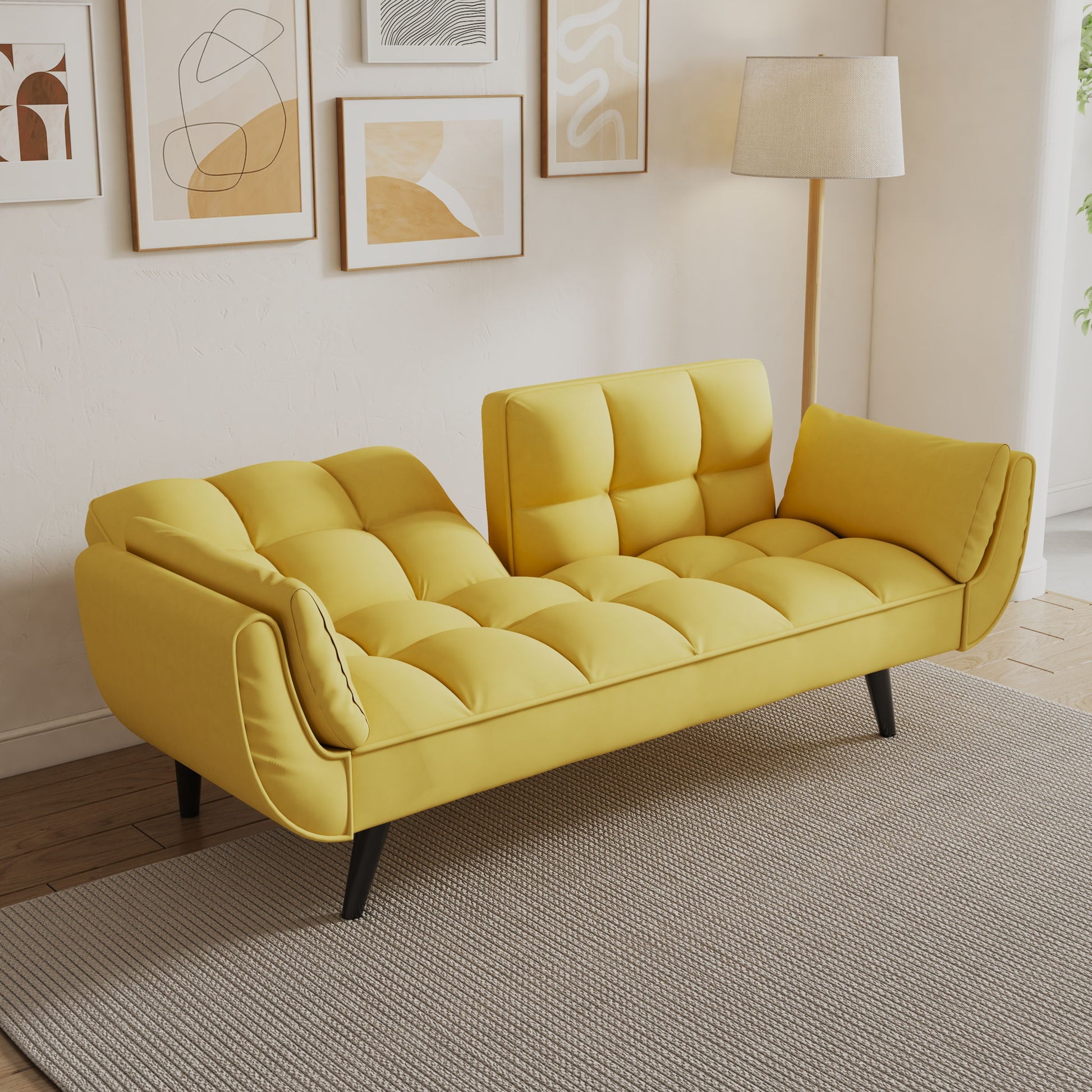 The Sofa Soft with two armrests and throw pillow offers comfort and a modern touch, fitting small spaces or apartments. It sits on a light gray rug with abstract art prints behind it, set against cream walls and wooden flooring.