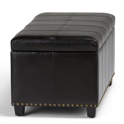 The Amelia - Transitional Storage Ottoman Bench features a rectangular black leather design with visible stitching, nailhead trim along the bottom edge, and short black legs.