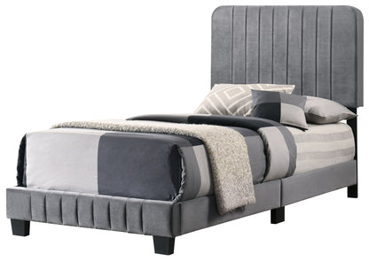 The Lodi - Bed features a tall, vertically paneled gray upholstered headboard, matching gray bed frame, and is styled with coordinated gray and white bedding, pillows, and a textured throw blanket.