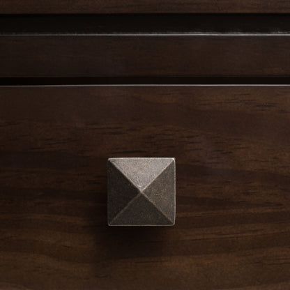 A close-up of the Cosmopolitan - Multipurpose Table featuring a square, metallic drawer knob with a pyramid-shaped design on a dark wooden drawer.