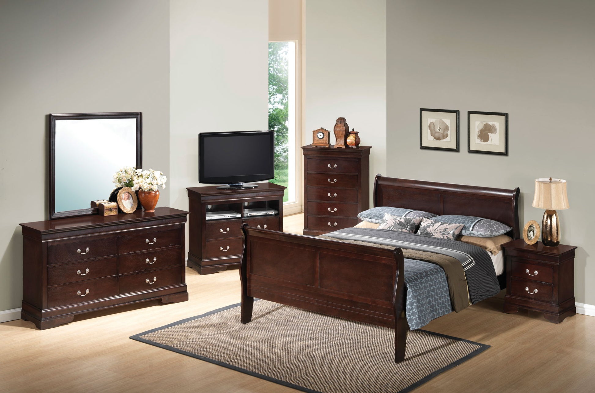 A bedroom featuring a Panel Sleigh Bed, two nightstands, a dresser with mirror, tall chest of drawers, and TV stand. Neutral walls, large window, and framed art above the bed complete the look.