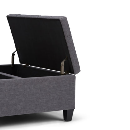The Harrison Upholstered Coffee Table Storage Ottoman, shown in gray with a hinged lid open to reveal interior storage, features short black legs and is displayed against a white background.