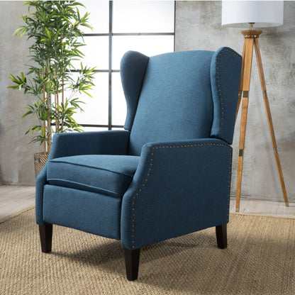 The Westeros Wing Back Fabric Upholstered Recliner with nailhead trim sits on a woven rug in a modern room, accented by a tall plant, floor lamp, and large windows in the background.