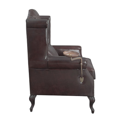 A side view of the Couch.com Pino Vintage Top Grain Leather Accent Chair in dark brown faux leather with curved wooden legs and a small round wooden tray attached by a spade-shaped metal arm.