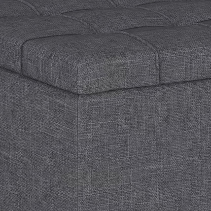 Close-up of the corner of the Harrison Upholstered Coffee Table Storage Ottoman, featuring dark gray textured fabric and a tufted, cushioned top.