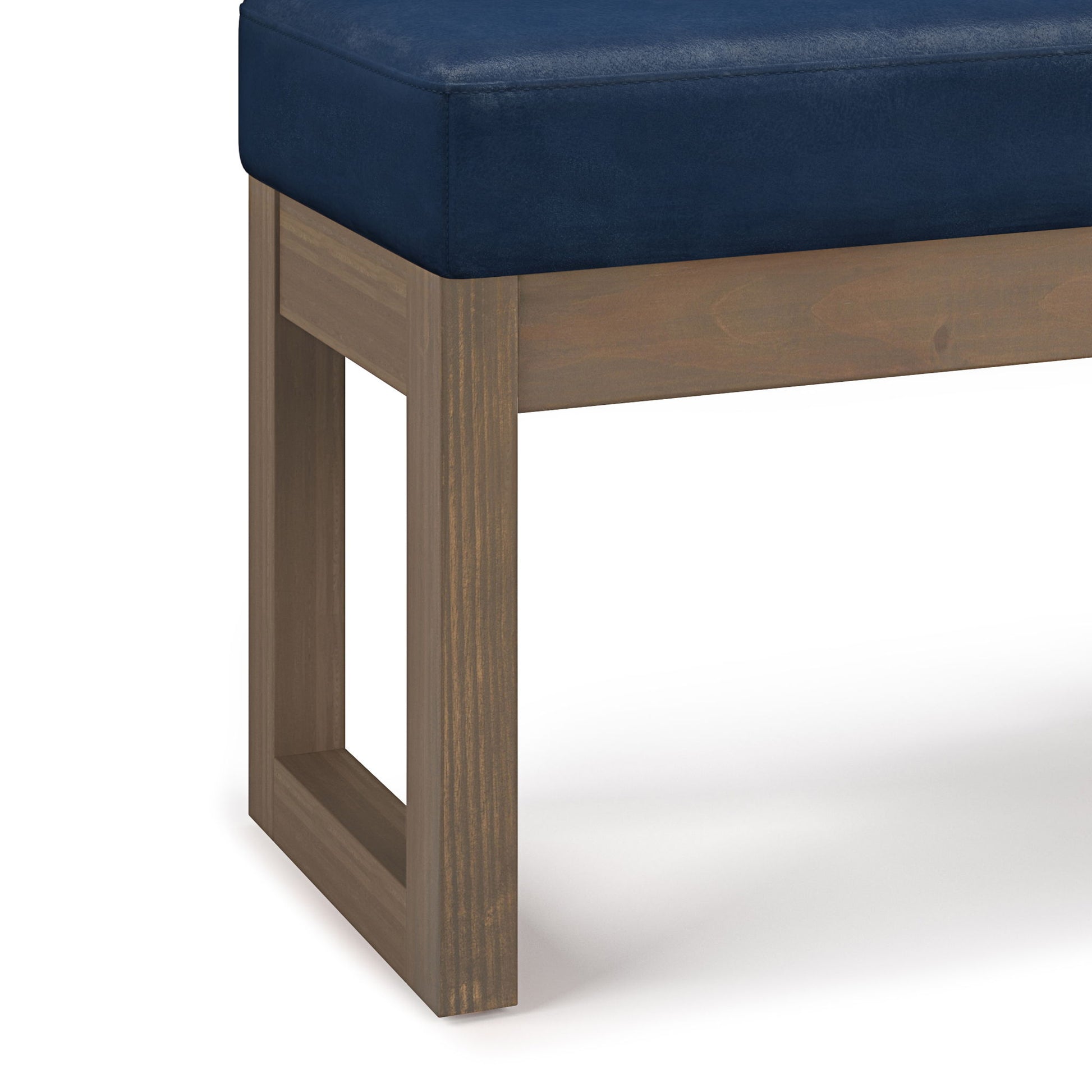 A close-up of the Milltown Upholstered Ottoman Bench, showcasing its navy blue cushioned seat and wooden legs with a rectangular cutout design.