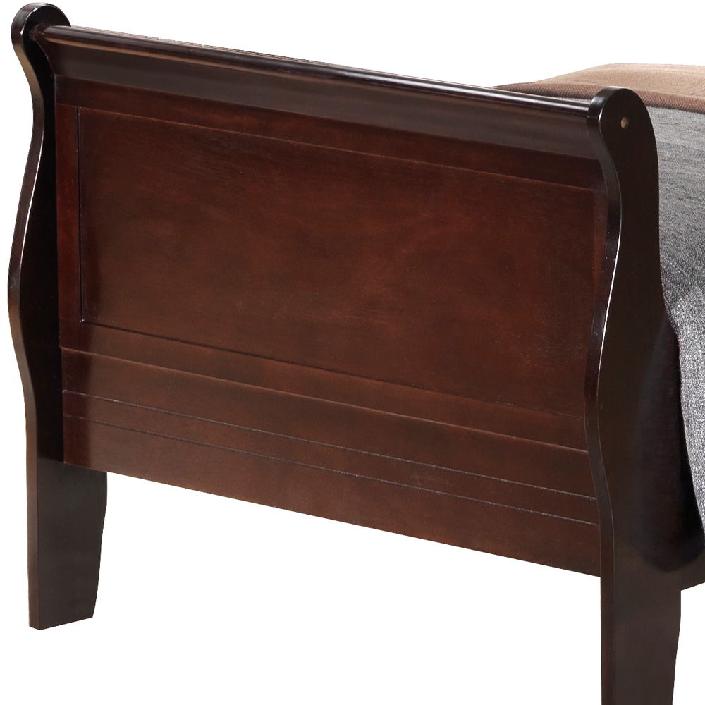 The image features the footboard of the Panel Sleigh Bed, crafted from dark brown wood with a polished finish and curved edges. A blanket is draped over one corner of the bed.