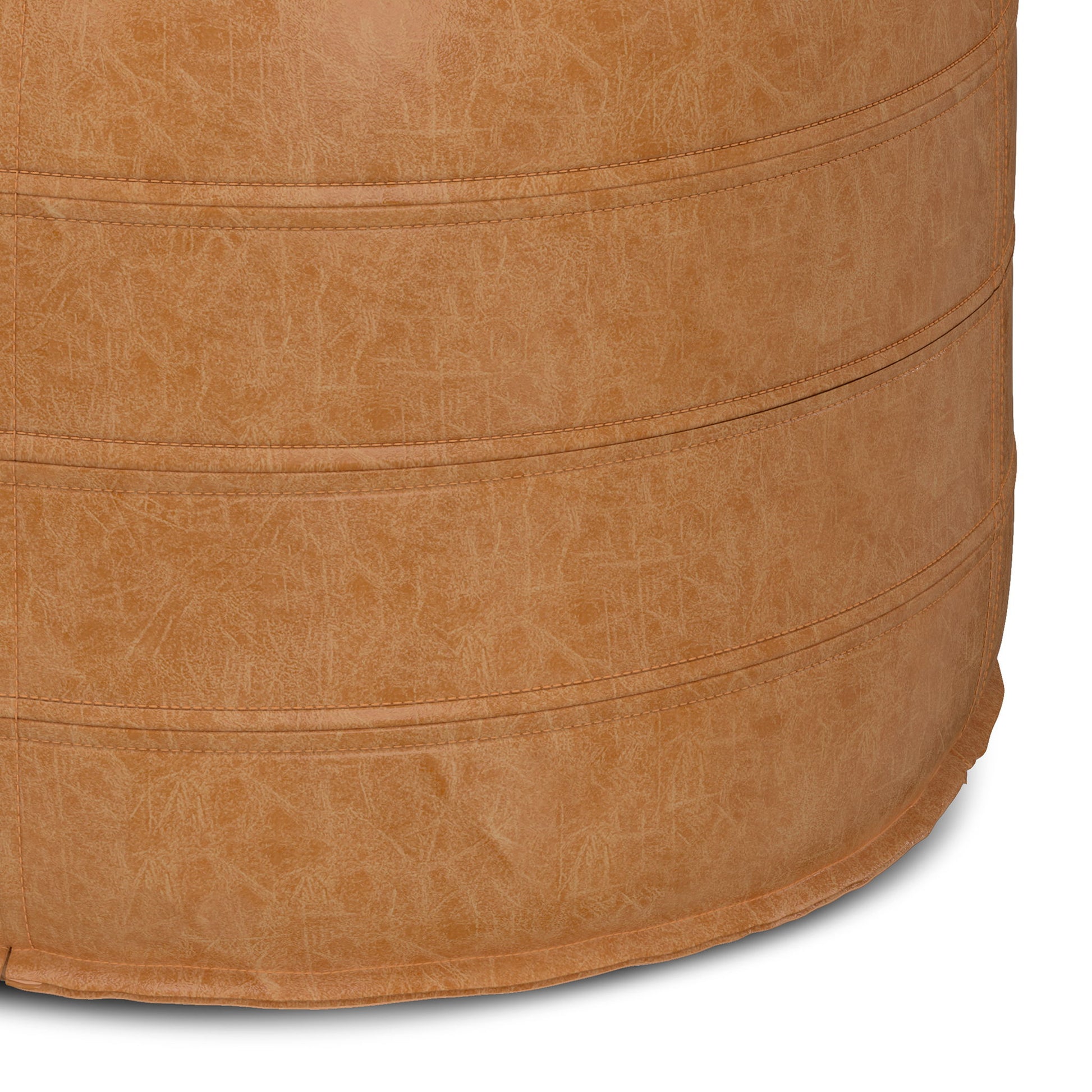 Close-up of the Brody - Round Pouf showcases its tan faux leather, visible stitching, and textured surface, emphasizing the material and fine craftsmanship of this stylish furniture piece.
