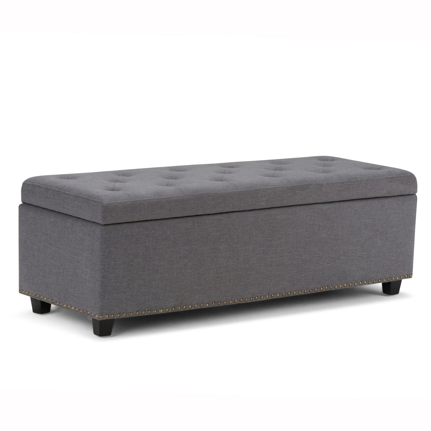 The Hamilton Upholstered Storage Ottoman features a gray tufted top, short black legs, and decorative brass nailhead trim along the bottom edge, shown on a white background.