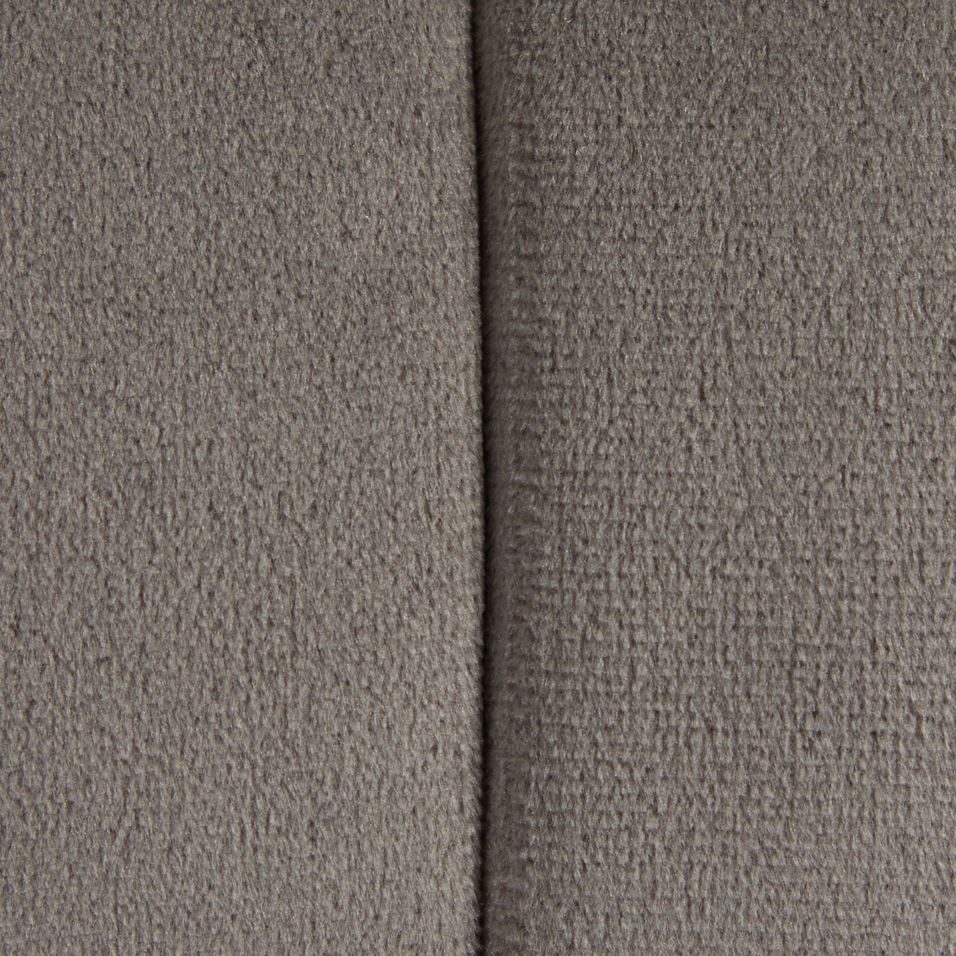 Close-up of the Braided - Versatile Round Ottoman’s textured gray fabric with a vertical seam down the center, dividing its surface into two sections.