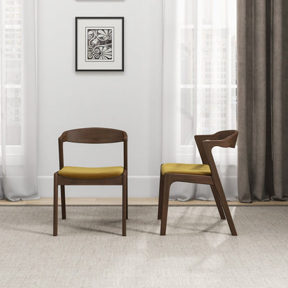 A set of two Dakota Mid-Century Modern Velvet Dining Chairs sits in a bright room with large windows, sheer white curtains, and a gray curtain. A framed abstract artwork hangs on the wall behind the chairs.