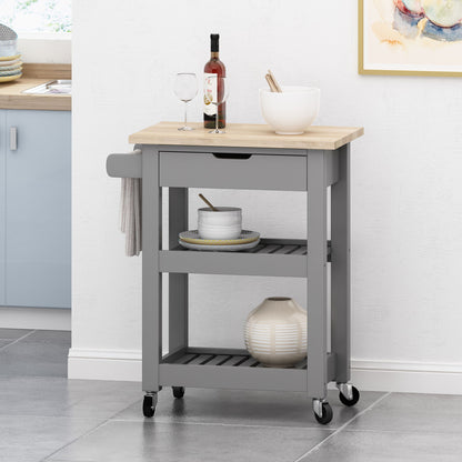 The Tattnall Kitchen Cart With Wheels features a compact gray frame, light wood top, two shelves, a side towel bar, storage for kitchen items, and four black wheels—perfect beside the counter on a tiled floor.