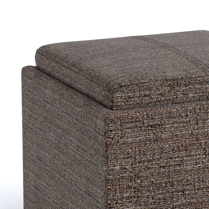 A close-up of the Rockwood - Upholstered Cube Storage Ottoman With Tray in brown textured fabric, featuring a removable lid, detailed stitching, and a modern boxy design against a white background.