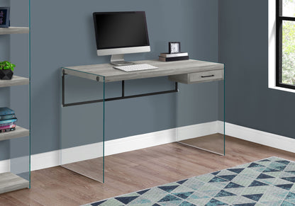 The Contemporary Design Computer Desk for Home Office features storage drawers, a light wood finish, glass side panels, and ample space for your computer setup. Perfect beside a window or bookshelf on a wooden floor.
