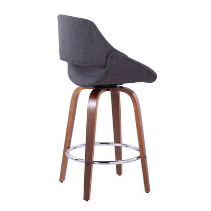 The Fabrico Mid Century Modern Counter Stool Set features curved, padded dark gray fabric seats, wooden legs, and round chrome footrests. Shown from a rear side angle against a white background (set of 2, fixed height).