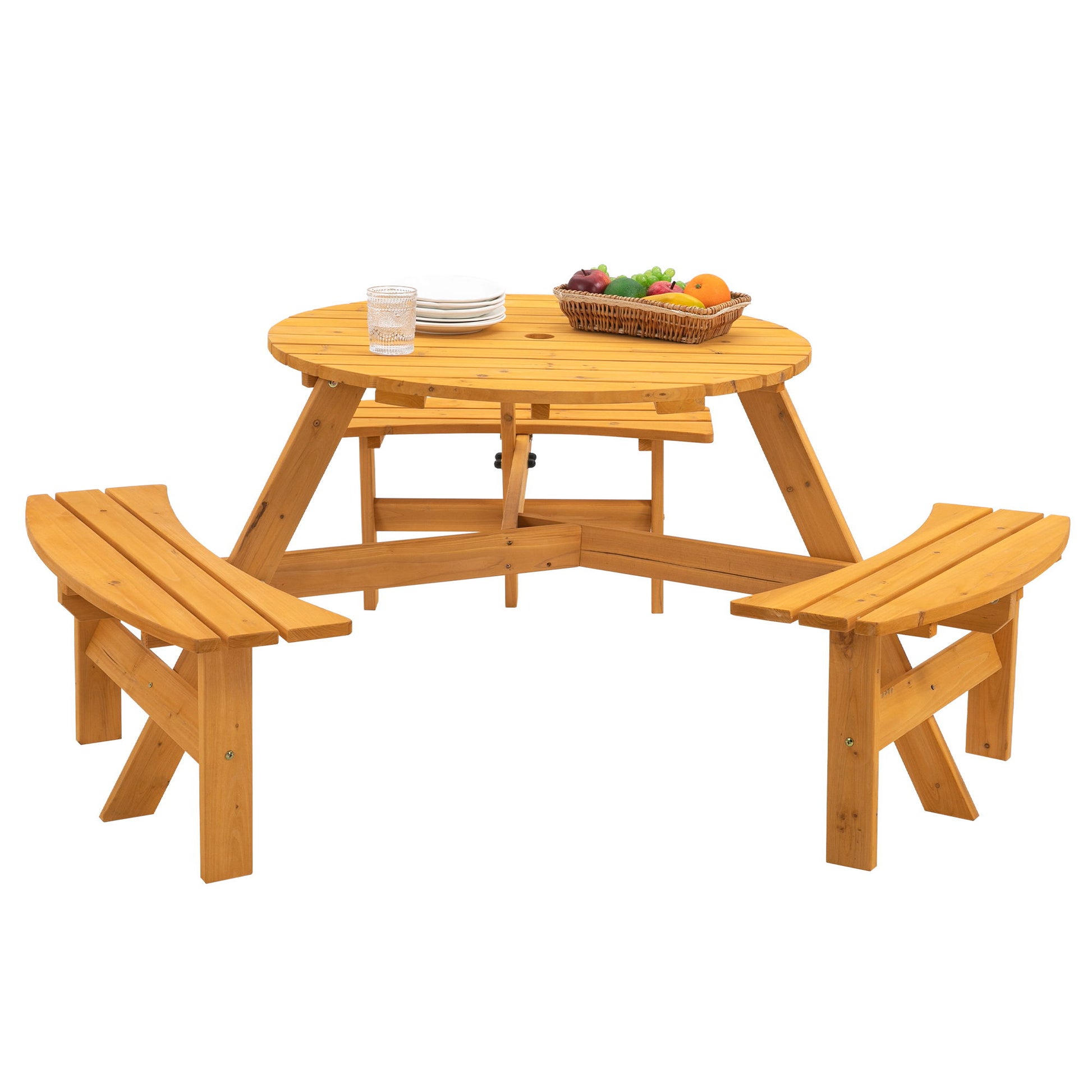 The 6 Person Circular Outdoor Wooden Picnic Table features three built-in benches and holds stacked white plates, a glass, and a basket of assorted fruits. Set against a plain white background.