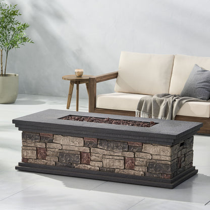 A Fire Pit With Lightweight Concrete And Steel Frame, featuring a recessed area with lava rocks, sits in front of a cushioned wooden sofa draped with a gray throw and accompanied by a small side table holding a candle.