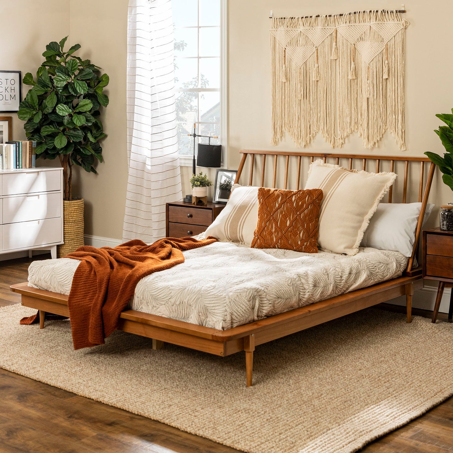 A cozy bedroom features the Mid-Century Modern Solid Wood Platform Bed Frame With Spindle Headboard, neutral bedding, an orange throw blanket, decorative pillows, a macrame wall hanging, plants, and abundant natural light for a warm vibe.