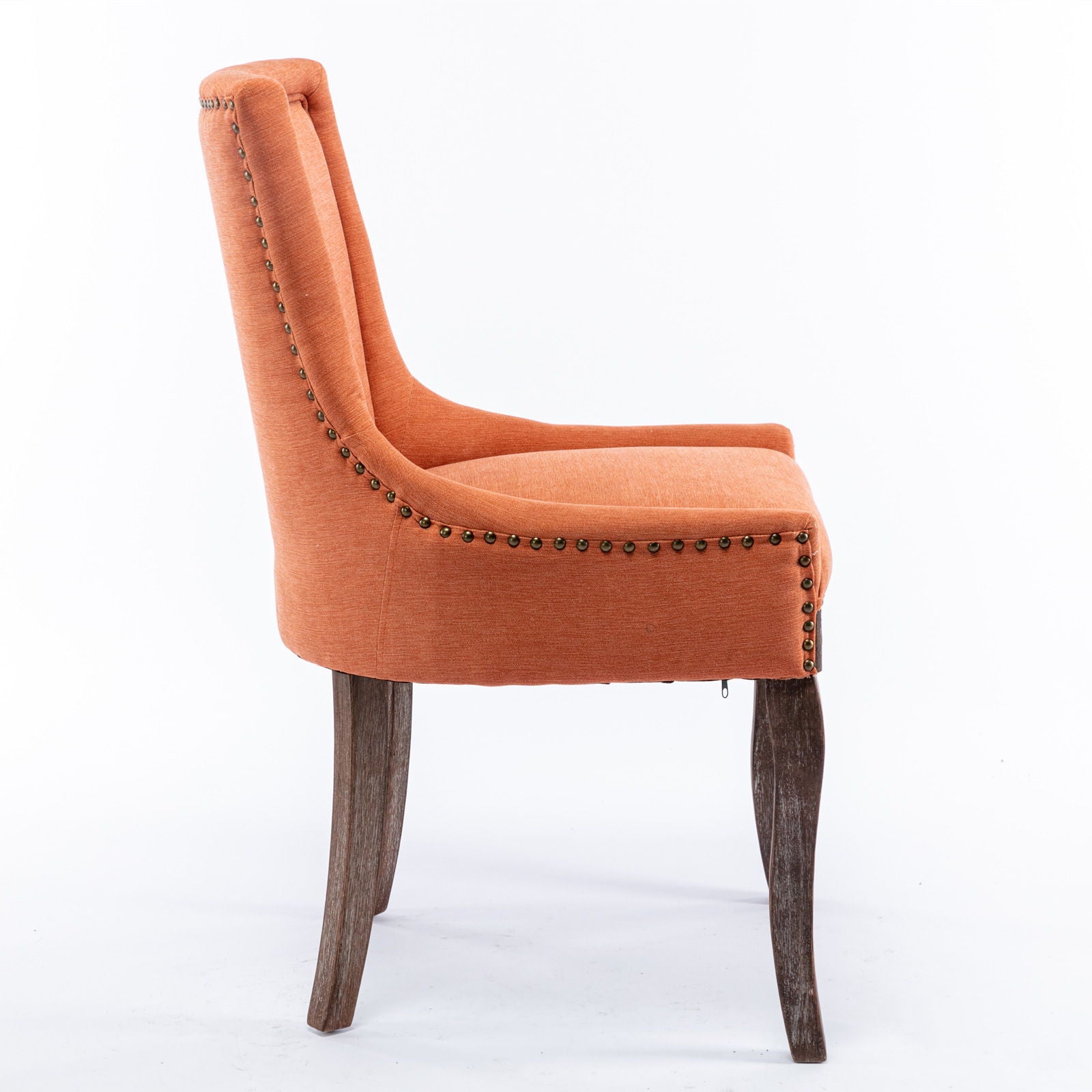 A side view of the Ultra Side Dining Chair, featuring thickened upholstery, neutrally toned solid wood legs, and bronze nailhead trim, set against a plain white background.