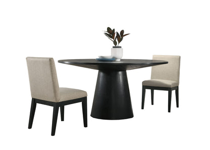 The Jasper dining set features a wide, contemporary round black table topped with a white vase and plates, paired with two beige fabric upholstered chairs with black legs on either side.