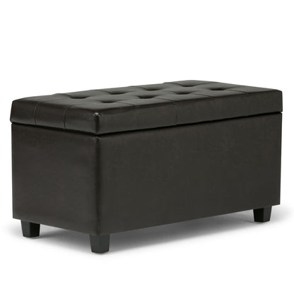 The Cosmopolitan Upholstered Storage Ottoman is rectangular, black, and tufted with short legs and a cushioned lid—ideal for storage or extra seating.