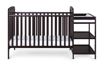 The Ramsey 3-in-1 Convertible Crib / Changer Combo features a dark wood finish, vertical slats, an attached changing table with three open shelves, a padded changing surface, and a crib mattress with a white patterned fitted sheet.