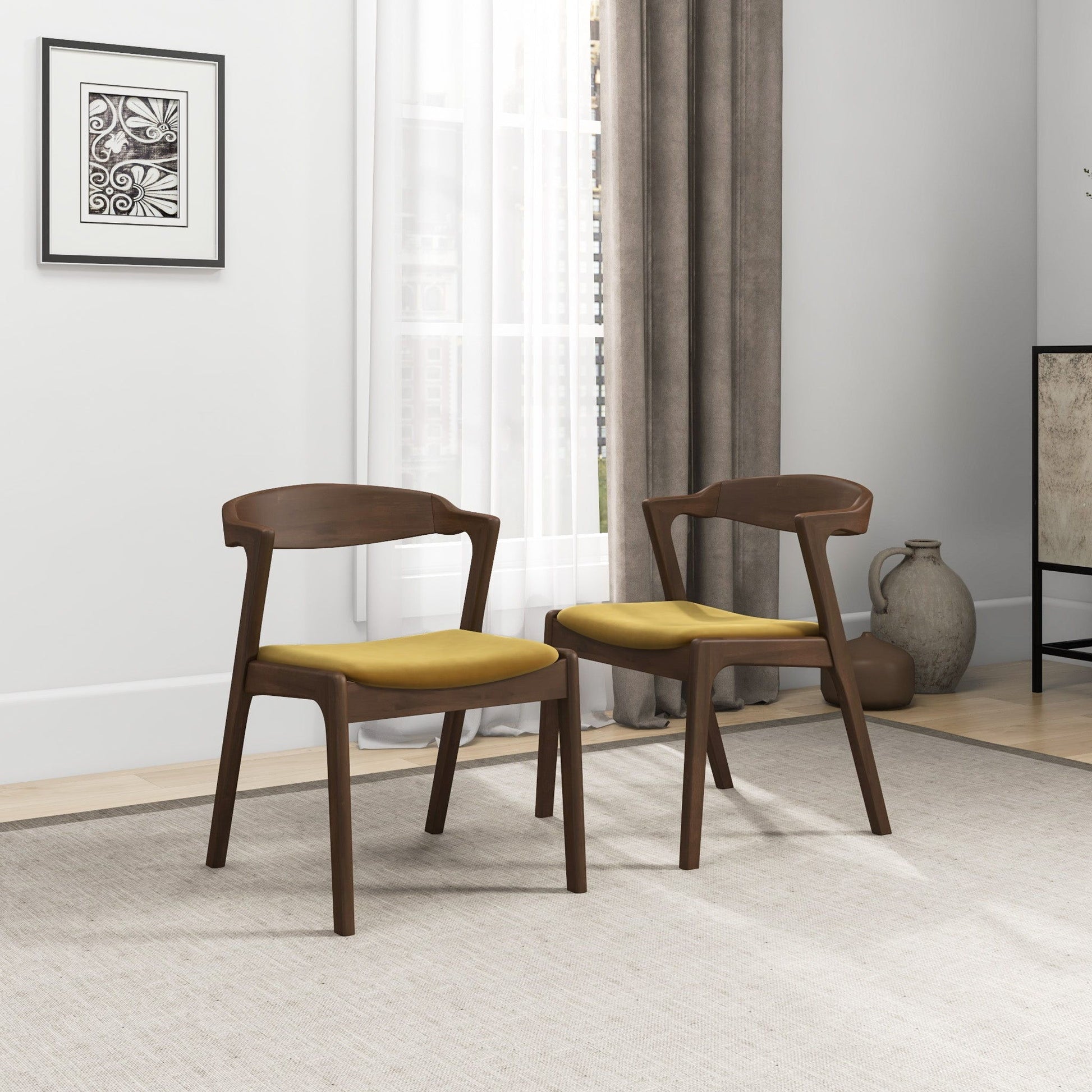A pair of Dakota Mid-Century Modern Velvet Dining Chairs are set on a light rug in a bright room with a large window, gray curtains, framed art, and decorative vases in the background.