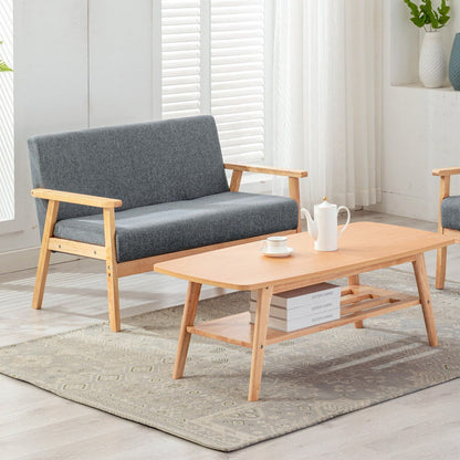 The Bahamas - Living Room Set features a light wood coffee table, gray cushioned wooden-arm sofa, patterned rug, tea set, white blinds and curtains, and decorative vases for a modern living room look.