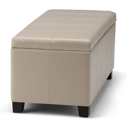 The Dover - Upholstered Storage Ottoman Bench is a rectangular beige ottoman with visible stitching and short, dark wooden legs, shown on a white background.