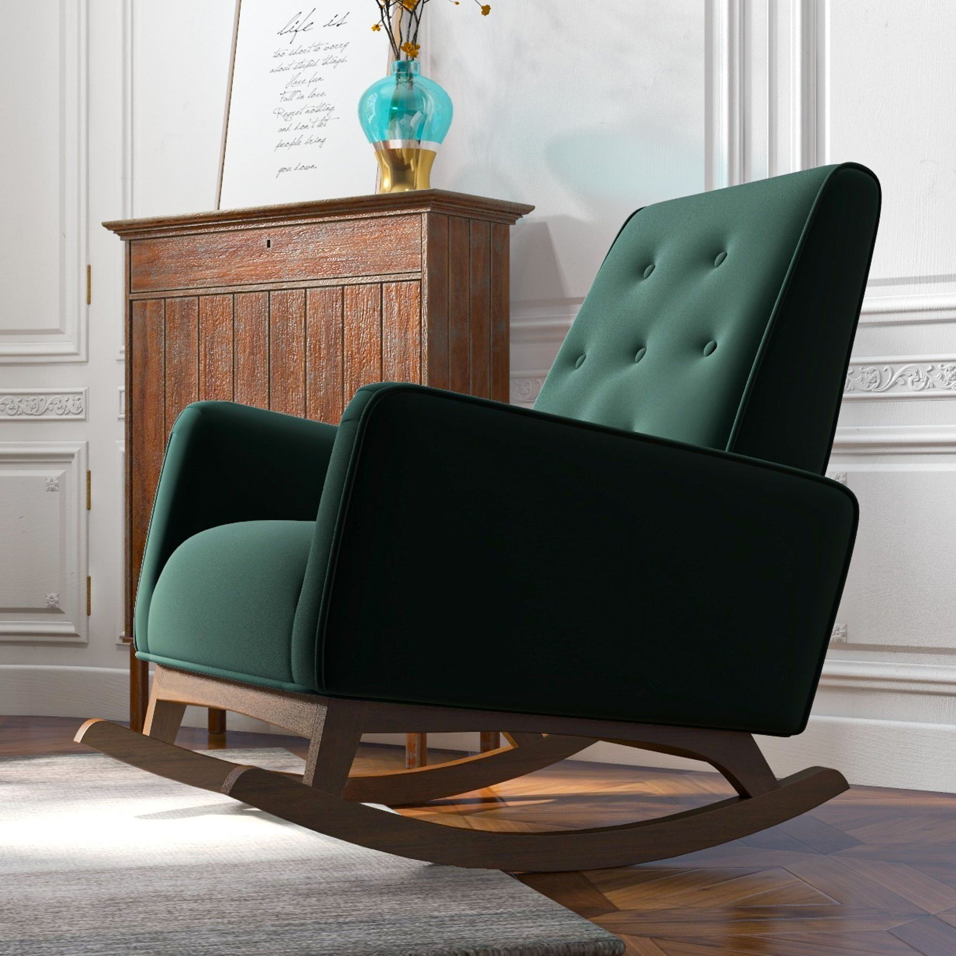 The Demetrius - Solid Wood Rocking Chair in dark green, featuring wooden legs, is placed on a hardwood floor beside a wooden cabinet, white paneled walls, and a turquoise vase with flowers.