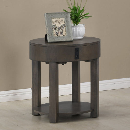 The Jonah MDF End Table With USB Ports in light brown, featuring a round design with four legs and a lower shelf, holds a framed butterfly picture and a small white planter with greenery against a beige wall and light floor.